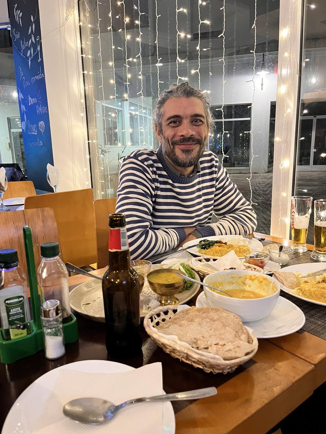 A guest at a table spread with dal, curry and freshly baked roti at Cozy Restaurant
